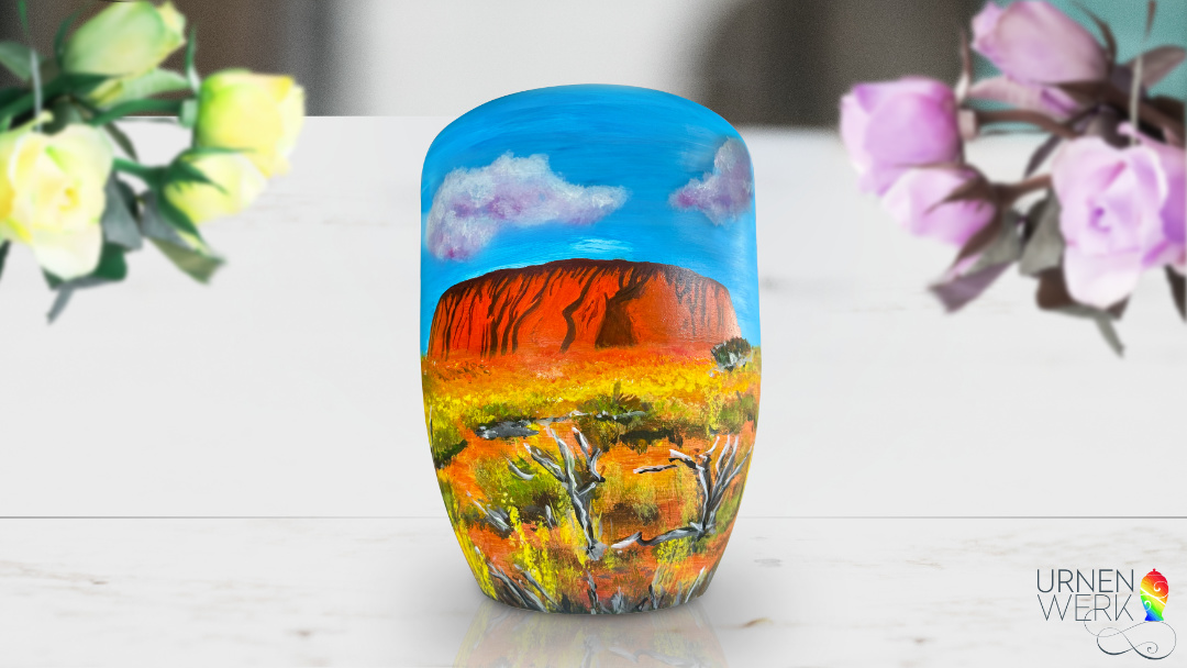 Der Ayers Rock mit Wolken, Gräsern und trockenen Bäumen.